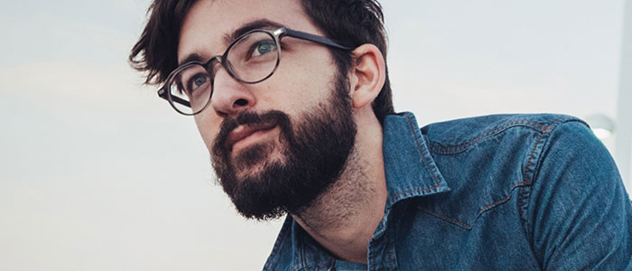 Een donkerharige man in een denim overhemd met een volle baard.